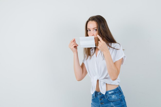 Bella dama con mascarilla en blusa blanca, jeans, vista frontal. espacio libre para tu texto