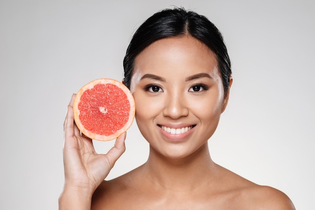 bella dama mostrando rodaja de pomelo