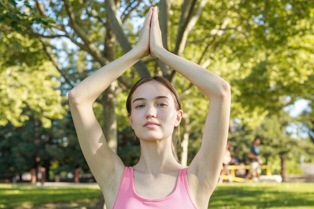 Bella dama de pie en el parque y mirando a la cámara