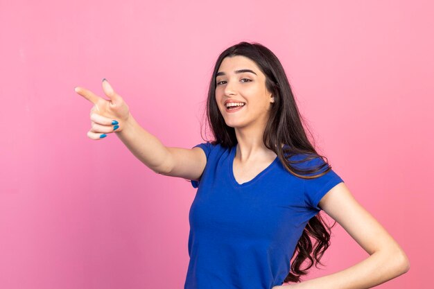 Bella dama señalando con el dedo a un lado y sonriendo a la cámara Foto de alta calidad