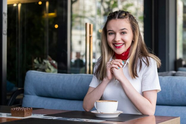 Bella dama sentada en el restaurante y sonriendo a la cámara