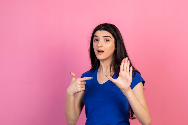 Una bella dama sosteniendo su mano abierta y señalándola con el dedo Foto de alta calidad