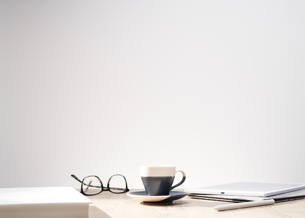 Bella foto de gafas ópticas y una taza en una mesa con un fondo blanco y espacio para el texto