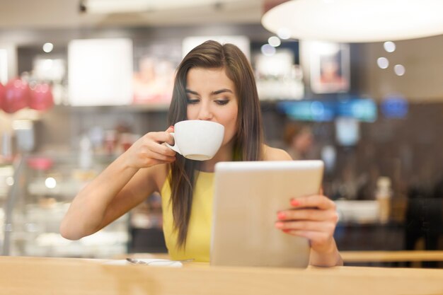 Bella mujer en café con tableta digital