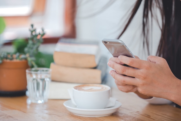 Una bella mujer con una camisa blanca de manga larga sentada en una cafetería.