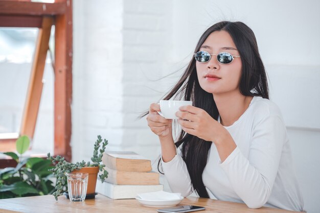 Una bella mujer con una camisa blanca de manga larga sentada en una cafetería.