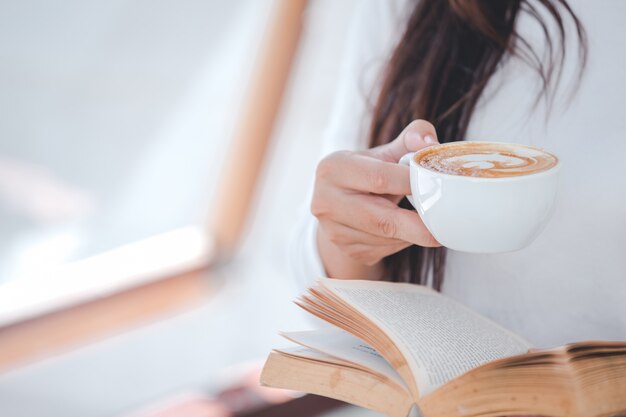 Una bella mujer con una camisa blanca de manga larga sentada en una cafetería.