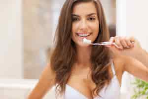 Foto gratuita bella mujer cepillarse los dientes en el baño.