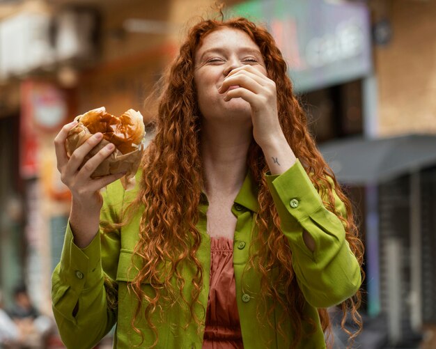 Bella mujer comiendo deliciosa comida callejera al aire libre