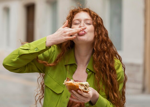 Bella mujer comiendo deliciosa comida callejera al aire libre