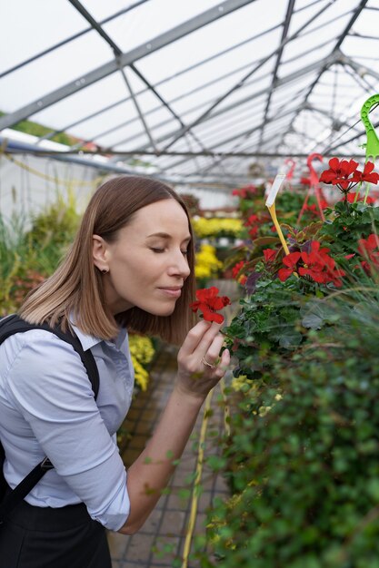 Bella mujer disfrutando de la belleza y el aroma de las flores en el invernadero.