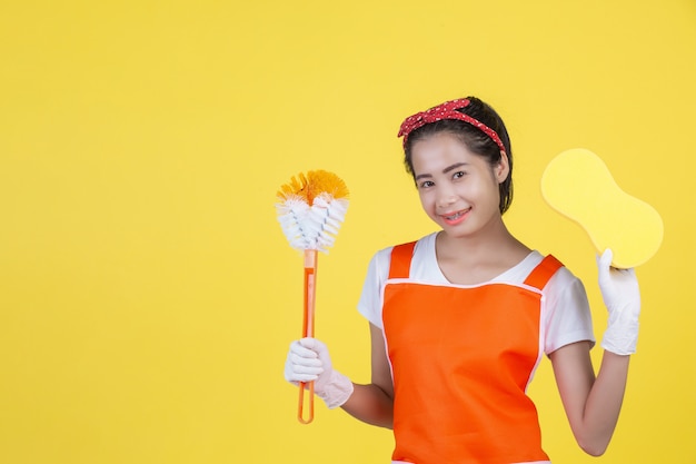 Una bella mujer con un dispositivo de limpieza en un amarillo