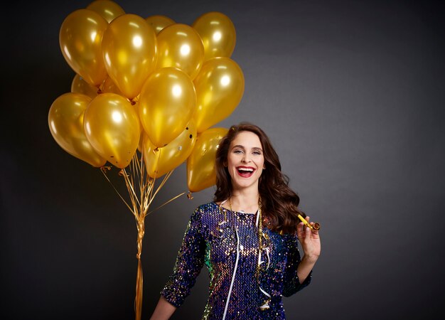 Bella mujer con globos dorados en tiro de estudio