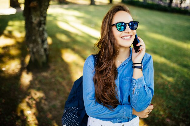 Bella mujer hablando por teléfono celular en el parque de verano