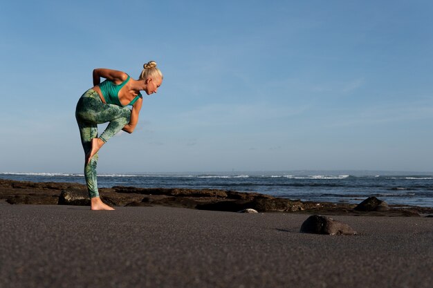 Bella mujer haciendo yoga en la playa