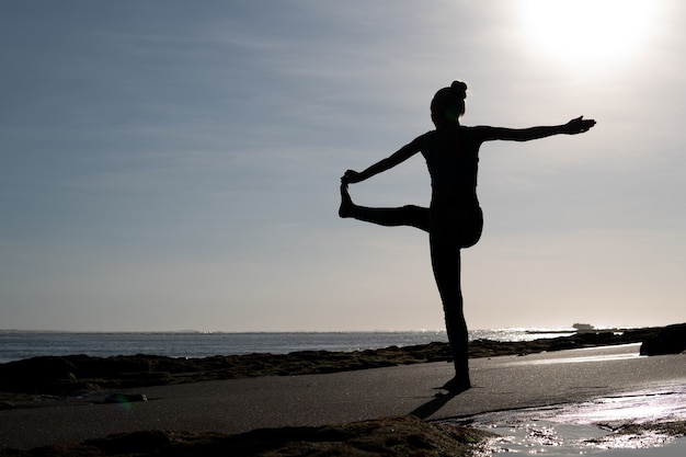 Bella mujer haciendo yoga en la playa