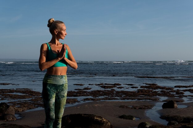 Bella mujer haciendo yoga en la playa