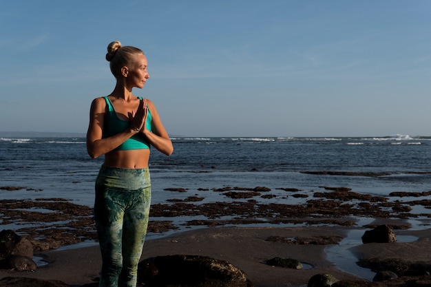 Bella mujer haciendo yoga en la playa