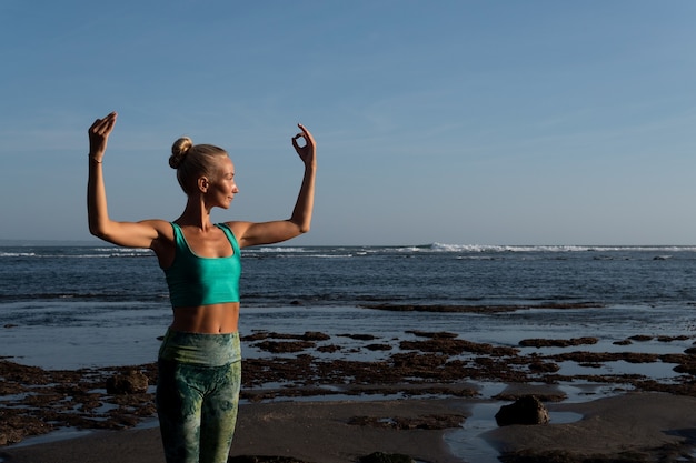 Bella mujer haciendo yoga en la playa