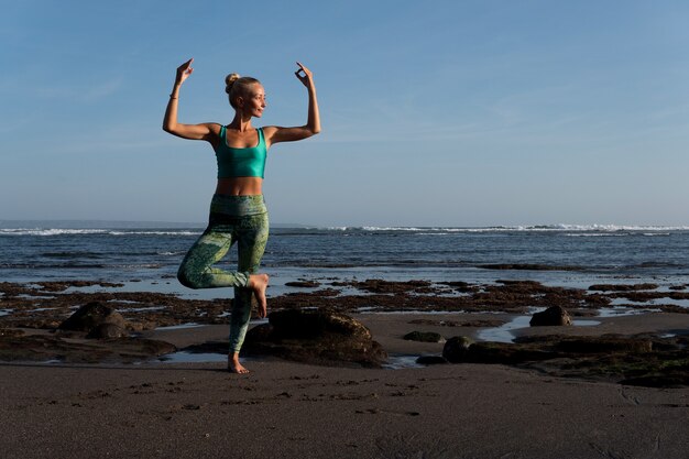 Bella mujer haciendo yoga en la playa