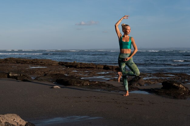 Bella mujer haciendo yoga en la playa