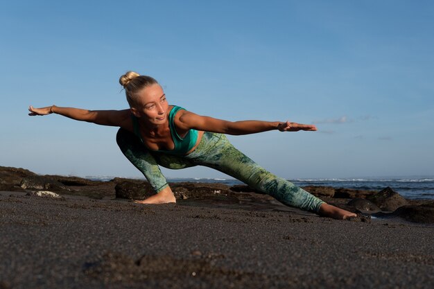 Bella mujer haciendo yoga en la playa