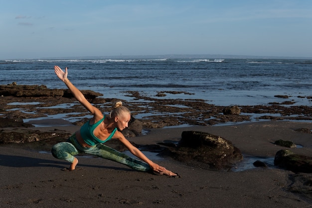 Bella mujer haciendo yoga en la playa