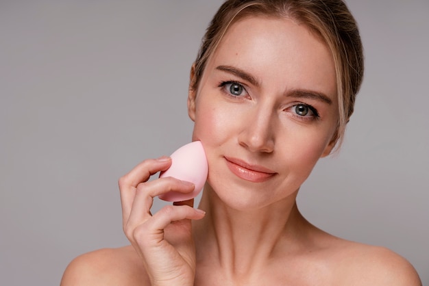 Bella mujer con una licuadora de maquillaje