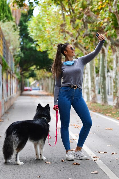 Bella mujer con una mascarilla quirúrgica tirada hacia abajo tomando una foto de sí misma