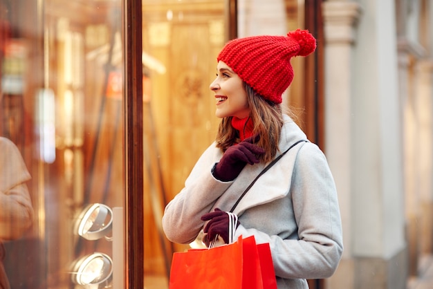 Bella mujer mirando el escaparate durante las compras de invierno