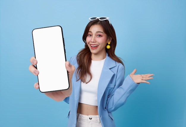 Bella mujer de negocios asiática mostrando una maqueta de teléfono inteligente de pantalla en blanco aislada sobre un fondo azul