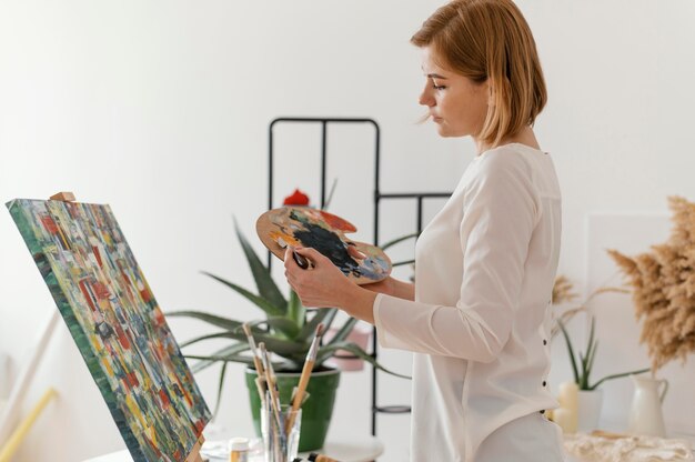 Bella mujer pintando con acrílicos sobre lienzo