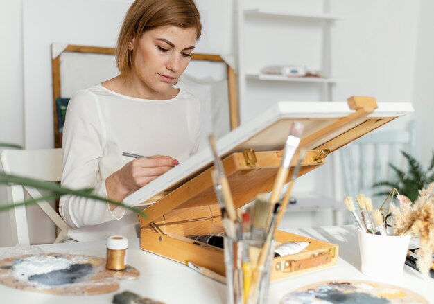 Bella mujer pintando con acrílicos sobre lienzo