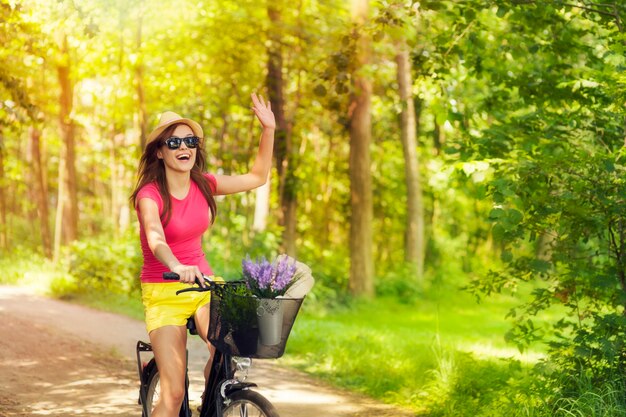 Bella mujer saludando a alguien durante el ciclismo