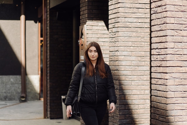 Bella mujer sonriente con smartphone caminando por la calle