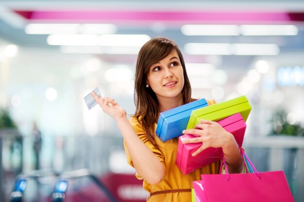 Bella mujer con tarjeta de crédito en el centro comercial