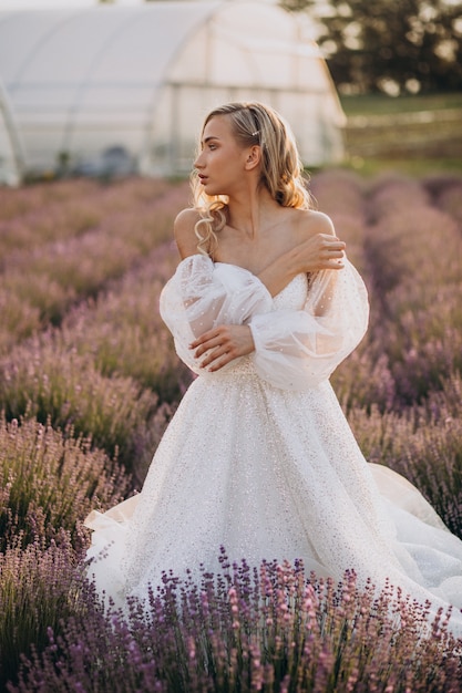 Bella mujer en vestido de novia en campo lavanda