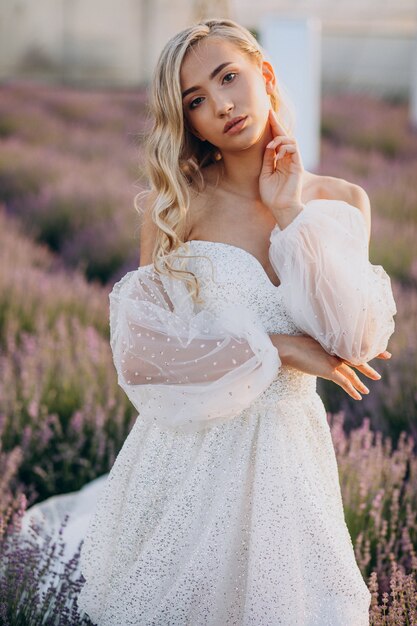 Bella mujer en vestido de novia en campo lavanda