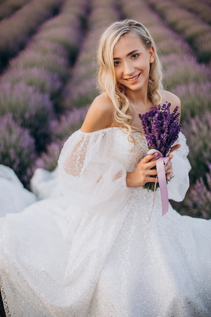 Bella mujer en vestido de novia en campo lavanda