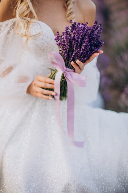 Bella mujer en vestido de novia en campo lavanda