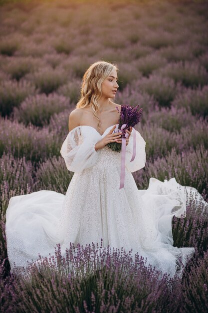 Bella mujer en vestido de novia en campo lavanda