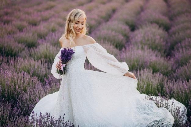 Bella mujer en vestido de novia en campo lavanda