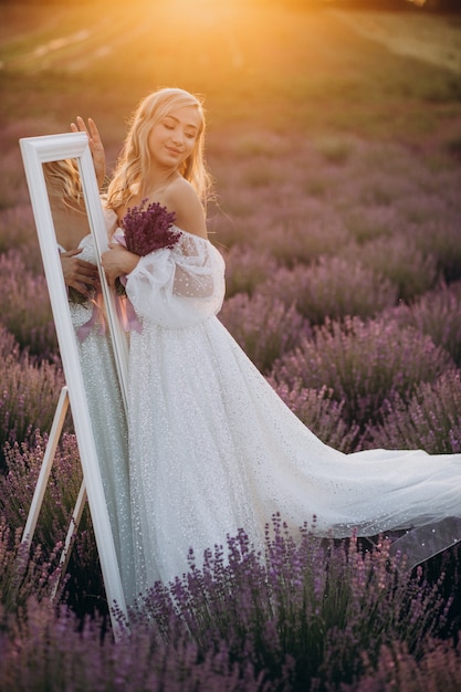 Bella mujer en vestido de novia en campo lavanda