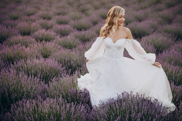 Bella mujer en vestido de novia en campo lavanda