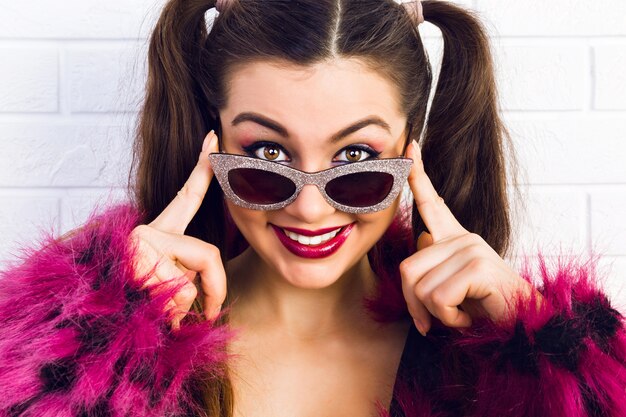 Belleza y estilo. Una hermosa joven sonriendo y ajustando sus gafas