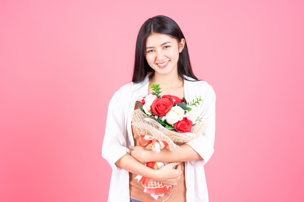 Belleza de la mujer asiática linda chica sensación feliz celebración flor rosa roja y rosa blanca sobre fondo rosa