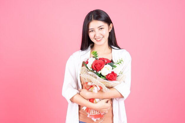 Belleza de la mujer asiática linda chica sensación feliz celebración flor rosa roja y rosa blanca sobre fondo rosa