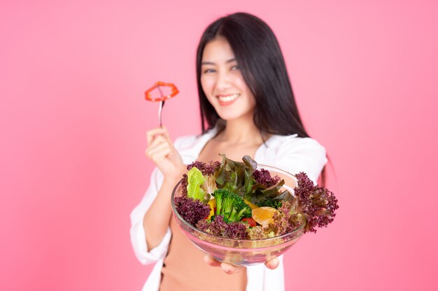 Belleza mujer asiática linda niña sentirse feliz comiendo dieta comida fresca ensalada para buena salud sobre fondo rosa