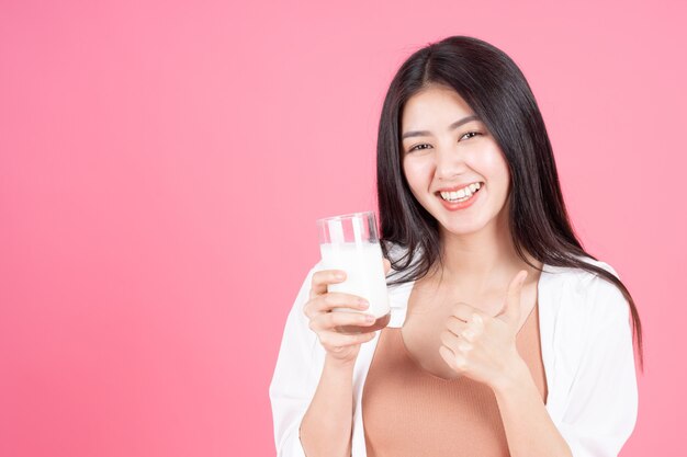 Belleza de la mujer asiática linda niña siente feliz bebiendo leche para una buena salud en la mañana sobre fondo rosa