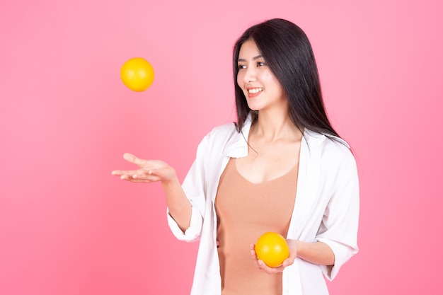 Foto gratuita belleza de la mujer asiática linda niña siente feliz holdind fruta naranja para una buena salud sobre fondo rosa